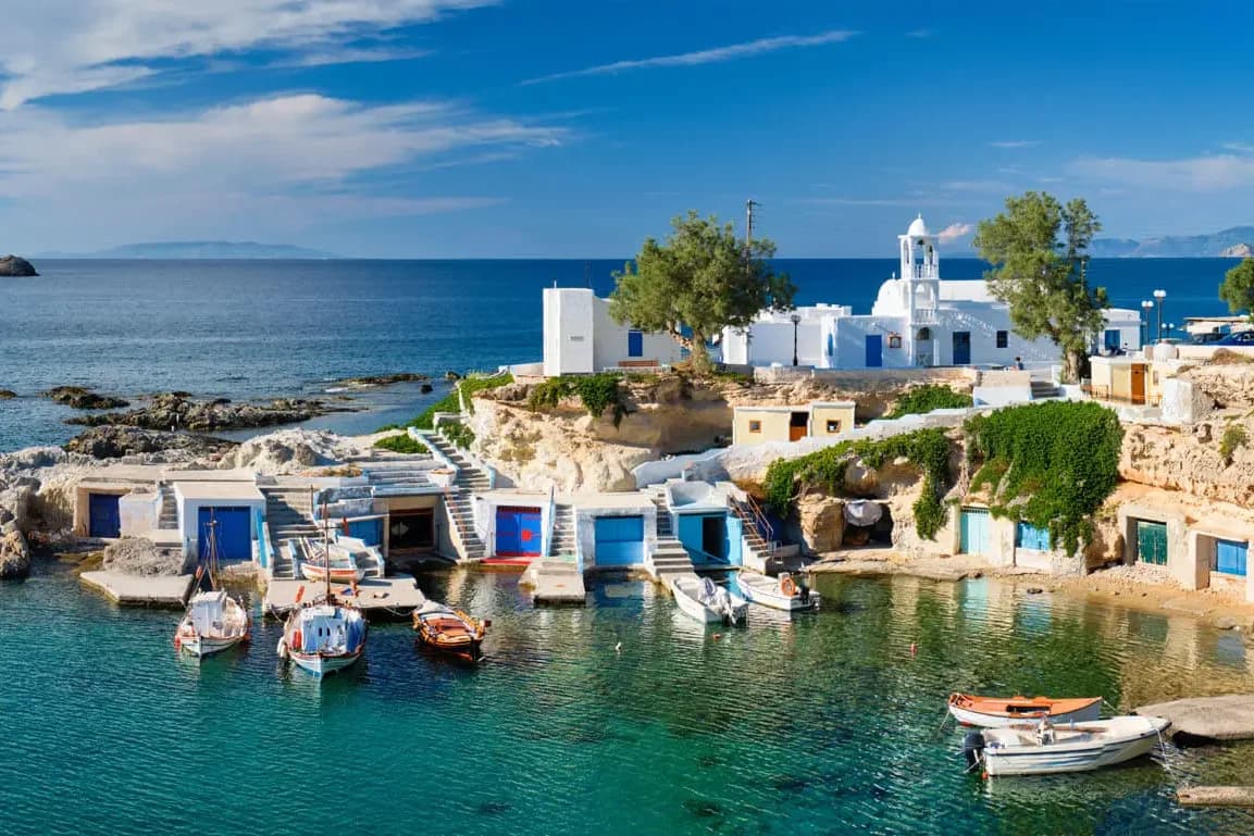 Painted boat houses and fishing boats on the coast of Milos